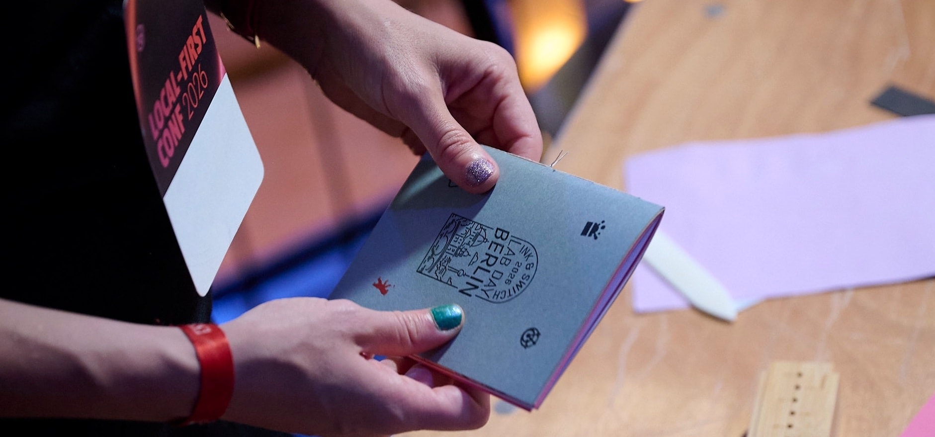 A close-up photo of someone holding a hand-made notebook, adorned with a "Ink & Switch 2026 Lab Day Berlin" stamp.
