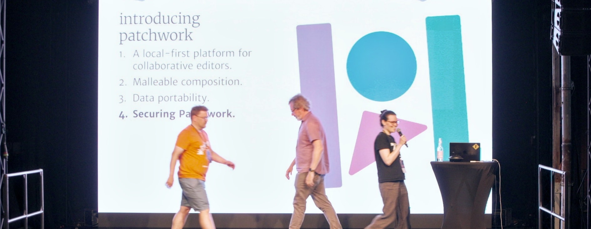 A still from the Patchwork presentation, showing three presenters crossing the stage.